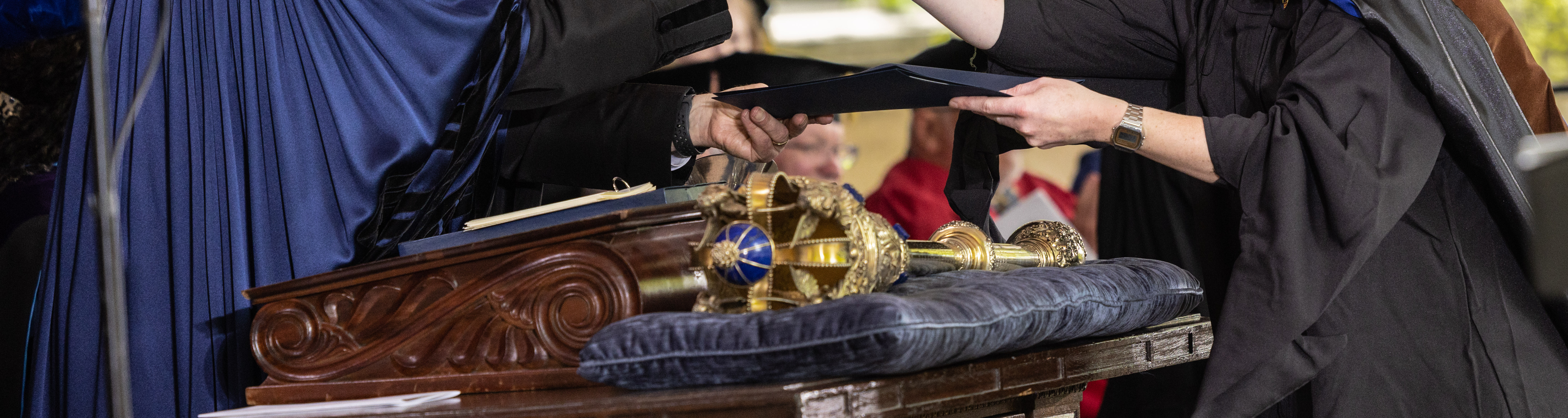 a cropped photo of Peter Salovey presenting a diploma at Yale commencement
