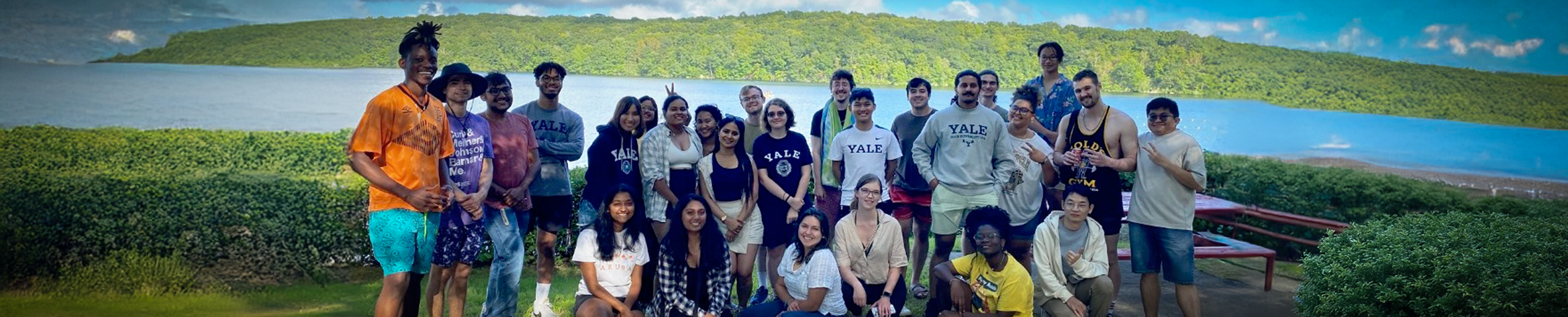 A group of people smiling in front of a lake