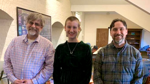 Three people standing in a hallway