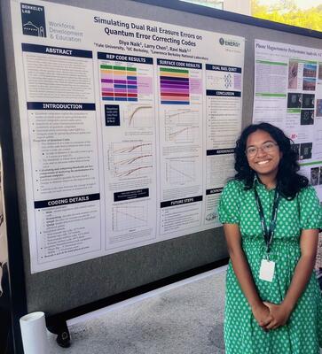 Diya Naik standing in front of poster.