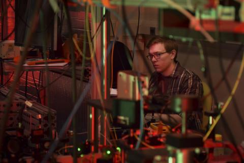 Graduate student David Mason hard at work in a web of lasers, lenses, wires, and computers within Professor Jack Harris’s lab. Photo by Jennifer Stergiou
